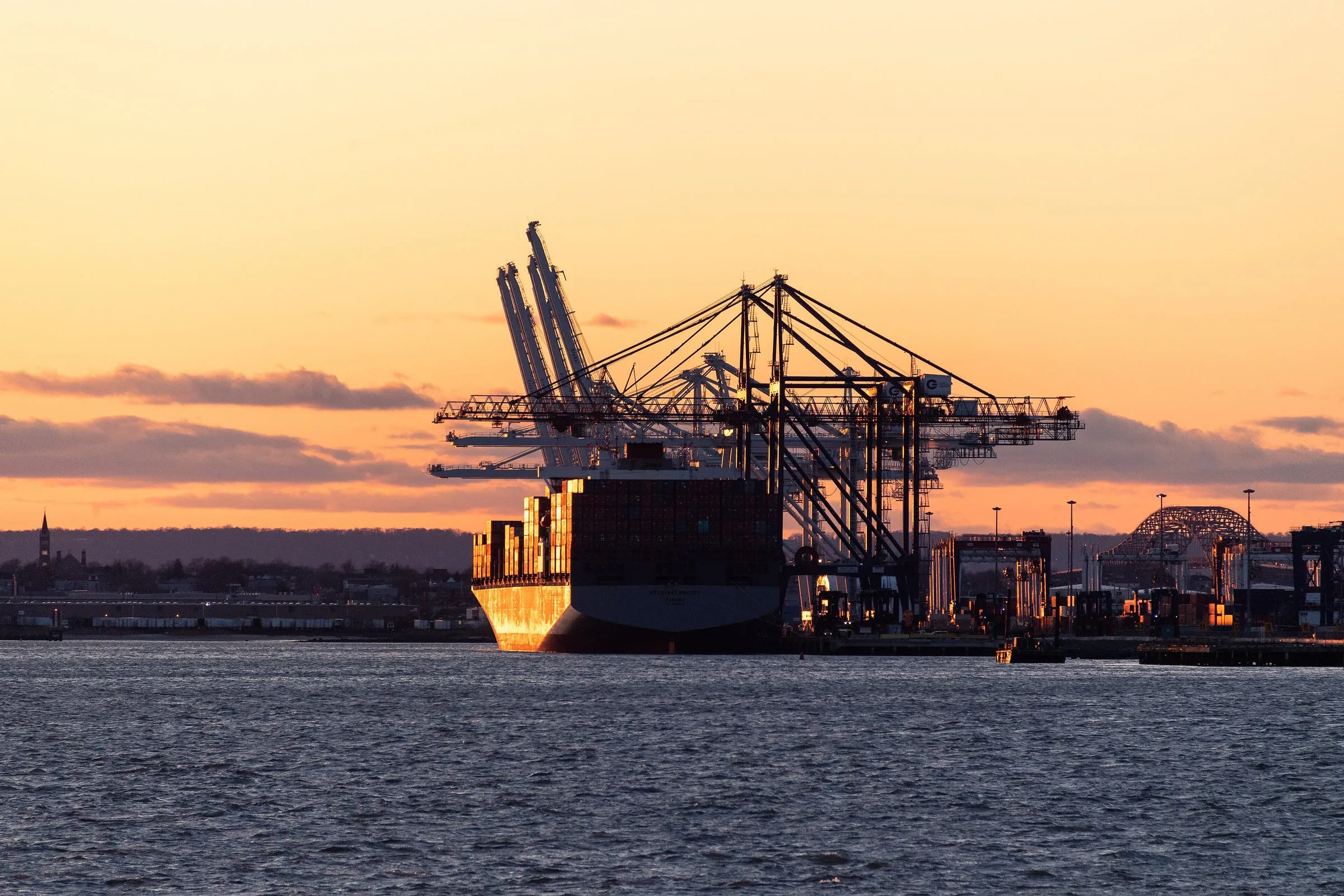 Buque portacontenedores atracado bajo grúas pórtico al atardecer