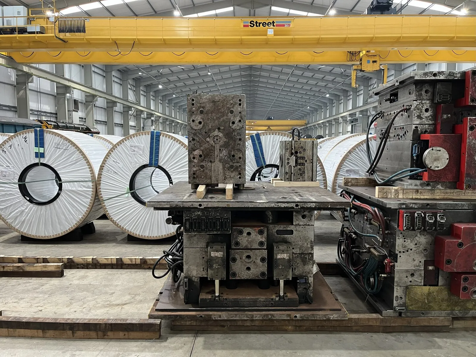 Nave industrial con bobinas de acero y matricería bajo puente grúa